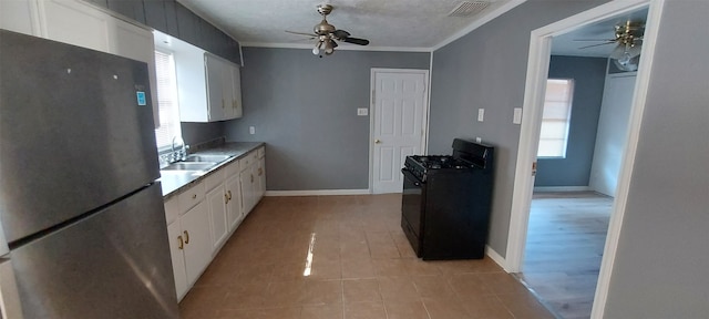 kitchen featuring white cabinets, sink, stainless steel fridge, ornamental molding, and gas stove