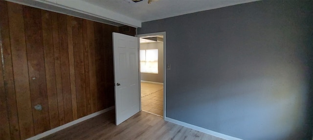 unfurnished bedroom with wood walls, light wood-type flooring, and a closet