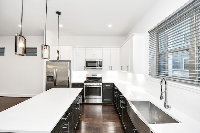 kitchen featuring stainless steel appliances, dark wood-type flooring, sink, decorative light fixtures, and white cabinetry