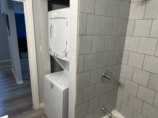 clothes washing area featuring hardwood / wood-style floors and stacked washer and clothes dryer