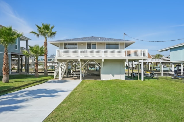 back of property with a balcony, a carport, and a lawn