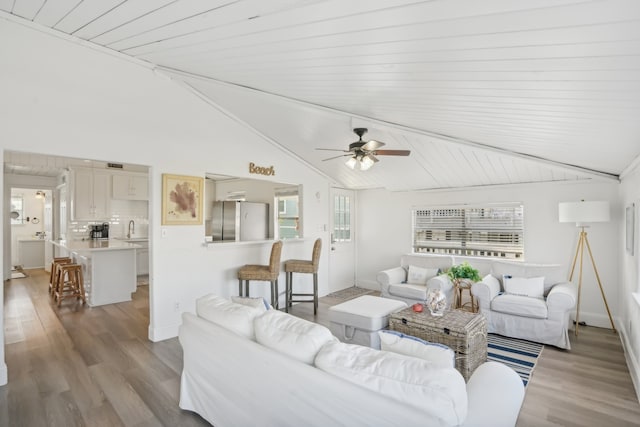 living room featuring sink, vaulted ceiling, light hardwood / wood-style flooring, and wood ceiling