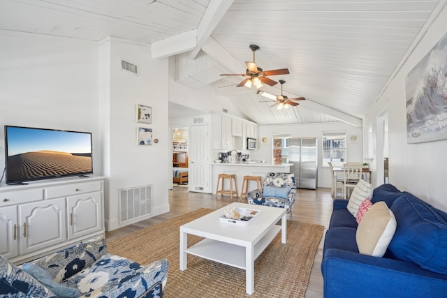 living room featuring vaulted ceiling with beams, ceiling fan, and wood-type flooring