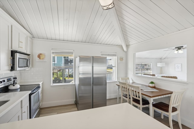 kitchen with backsplash, lofted ceiling with beams, light hardwood / wood-style flooring, appliances with stainless steel finishes, and white cabinetry