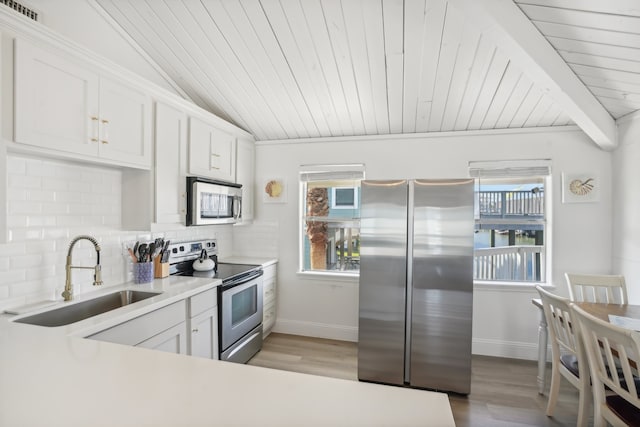 kitchen featuring light wood-type flooring, stainless steel appliances, sink, wooden ceiling, and white cabinetry