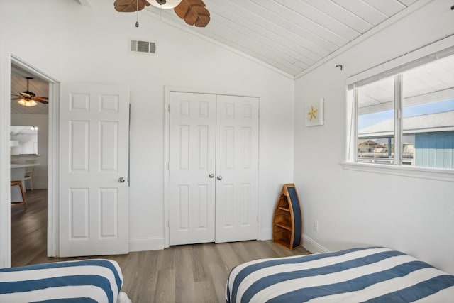 bedroom with wooden ceiling, lofted ceiling, ceiling fan, light hardwood / wood-style floors, and a closet