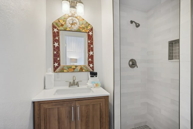 bathroom with a tile shower and vanity