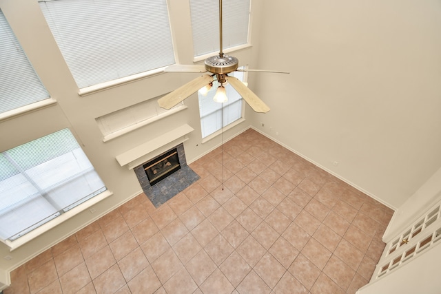 unfurnished living room featuring a tile fireplace, ceiling fan, and light tile patterned flooring