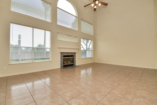 unfurnished living room featuring a tile fireplace, light tile patterned floors, and a high ceiling