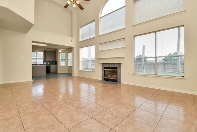 unfurnished living room featuring ceiling fan, light tile patterned floors, and a high ceiling