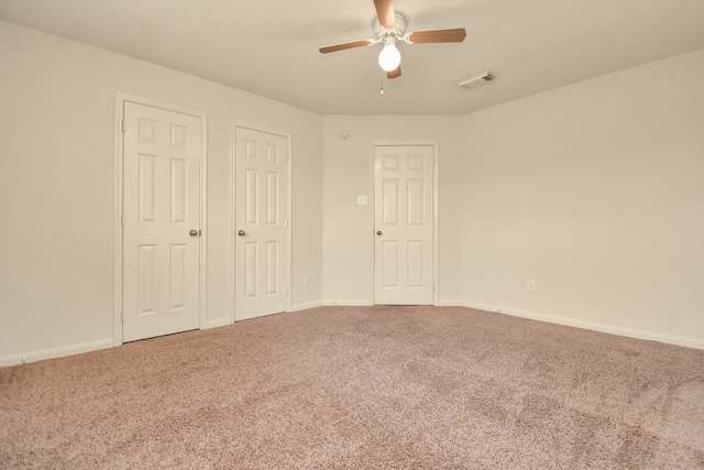 unfurnished bedroom featuring ceiling fan, carpet floors, and multiple closets