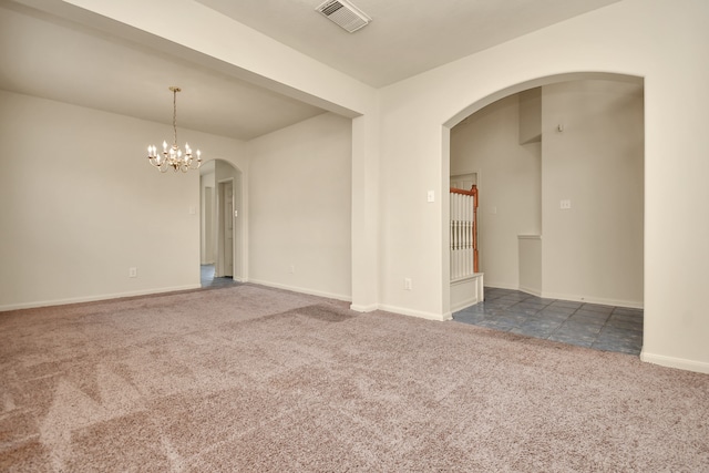 carpeted empty room featuring an inviting chandelier