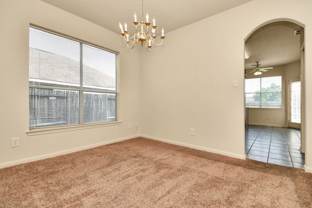 carpeted spare room featuring ceiling fan with notable chandelier