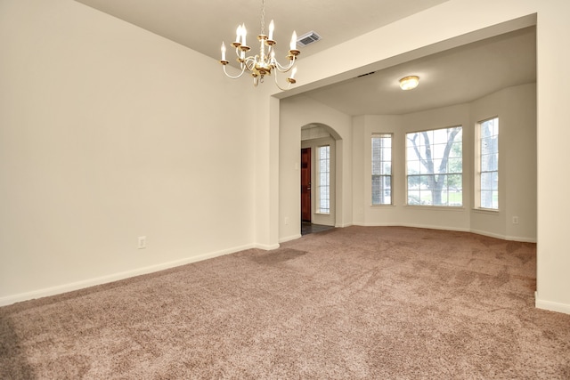 carpeted spare room with an inviting chandelier