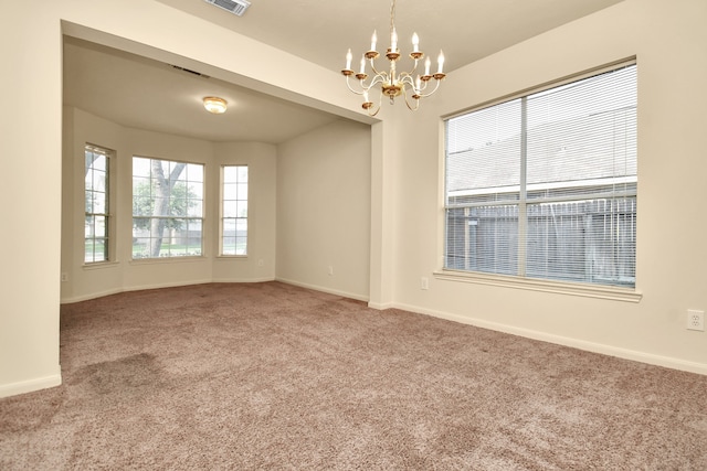 carpeted spare room with an inviting chandelier