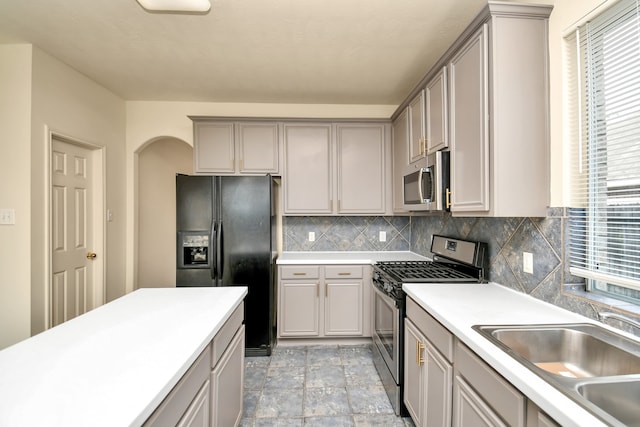 kitchen featuring gray cabinetry, decorative backsplash, sink, and appliances with stainless steel finishes