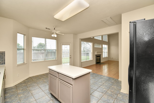 kitchen featuring black refrigerator, gray cabinetry, ceiling fan, light tile patterned floors, and a kitchen island