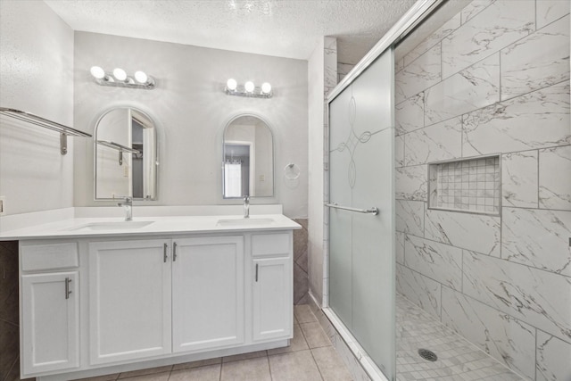 bathroom with tile patterned flooring, vanity, a textured ceiling, and walk in shower