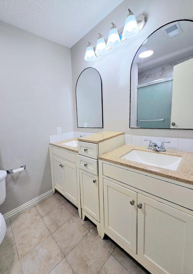 bathroom featuring tile patterned flooring, vanity, a textured ceiling, and toilet