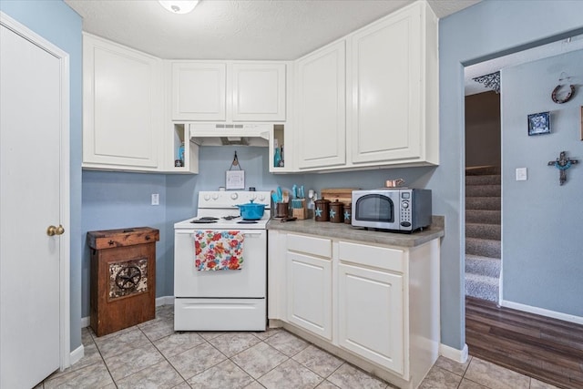 kitchen with electric range, white cabinets, and exhaust hood