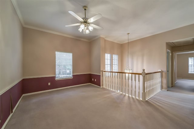 carpeted spare room with ornamental molding, ceiling fan, and a healthy amount of sunlight