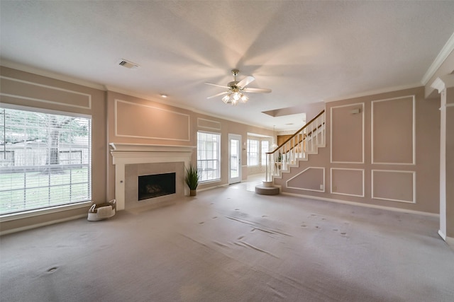 unfurnished living room featuring carpet flooring, crown molding, and a healthy amount of sunlight