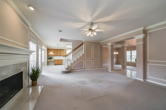 unfurnished living room featuring ceiling fan, crown molding, light colored carpet, and a fireplace