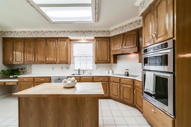 kitchen with stainless steel appliances, crown molding, sink, light tile patterned floors, and a kitchen island