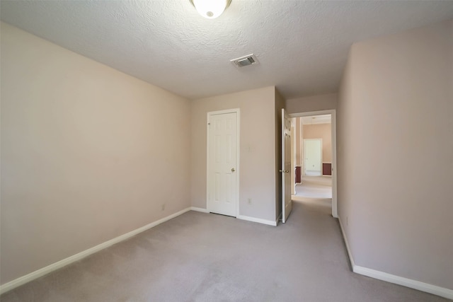 unfurnished bedroom with light colored carpet, a textured ceiling, and a closet