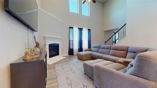 living room with a high ceiling, light hardwood / wood-style flooring, plenty of natural light, and ceiling fan