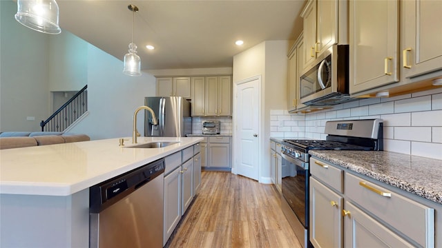 kitchen featuring stainless steel appliances, sink, pendant lighting, a center island with sink, and light hardwood / wood-style floors