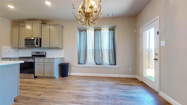 kitchen featuring backsplash, plenty of natural light, a notable chandelier, and appliances with stainless steel finishes