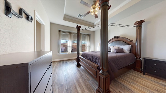 bedroom featuring a tray ceiling, ceiling fan, crown molding, and light hardwood / wood-style floors