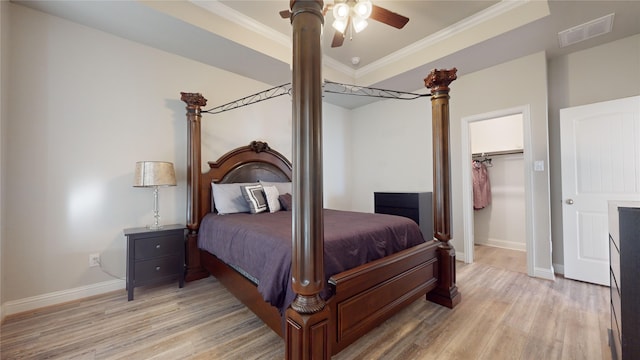 bedroom with ceiling fan, a spacious closet, light wood-type flooring, ornamental molding, and a closet