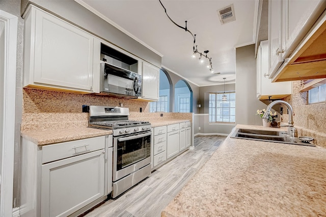 kitchen with crown molding, sink, white cabinets, and stainless steel range with gas stovetop