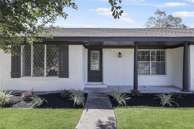 entrance to property with covered porch and a yard