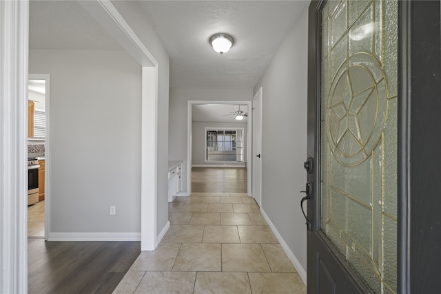 corridor with plenty of natural light, a textured ceiling, and light hardwood / wood-style flooring