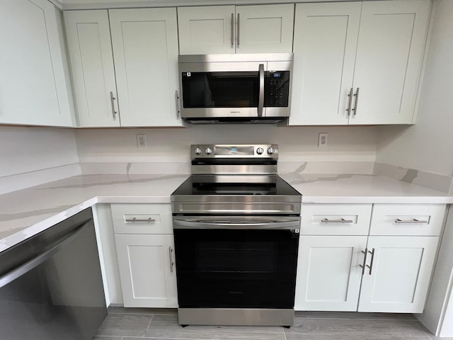 kitchen with white cabinetry, light stone counters, and appliances with stainless steel finishes