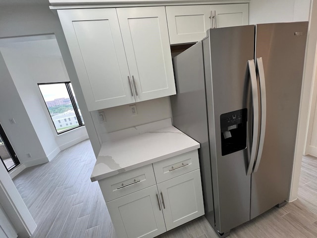 kitchen with white cabinetry, light stone counters, and stainless steel fridge with ice dispenser