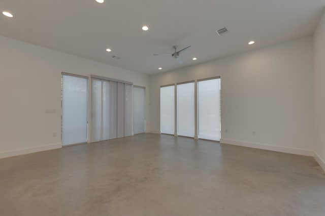 spare room with ceiling fan and concrete floors