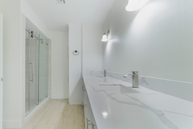 bathroom with vanity, a shower with shower door, and wood-type flooring