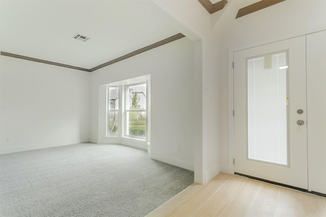 foyer entrance with ornamental molding and light colored carpet