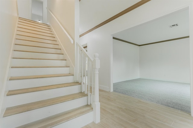 stairway featuring crown molding and carpet flooring