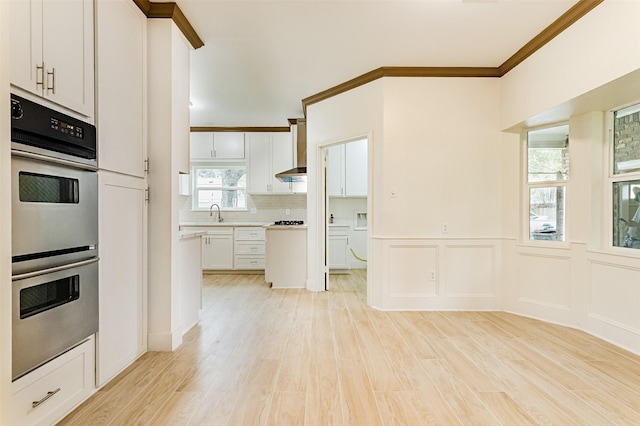 kitchen featuring white cabinetry, backsplash, light hardwood / wood-style flooring, and stainless steel double oven