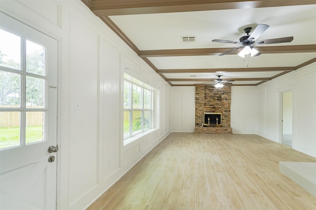 unfurnished living room featuring beamed ceiling, ceiling fan, light wood-type flooring, and a fireplace