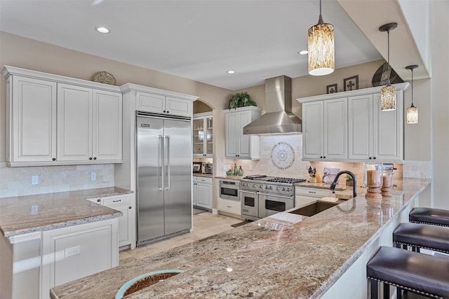 729 Pegasus Ln, League City, TX 77573 - kitchen with premium appliances, a sink, wall chimney exhaust hood, a peninsula, and light stone countertops