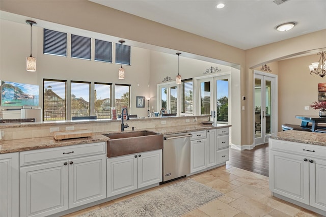 kitchen with stainless steel dishwasher, pendant lighting, white cabinetry, and sink