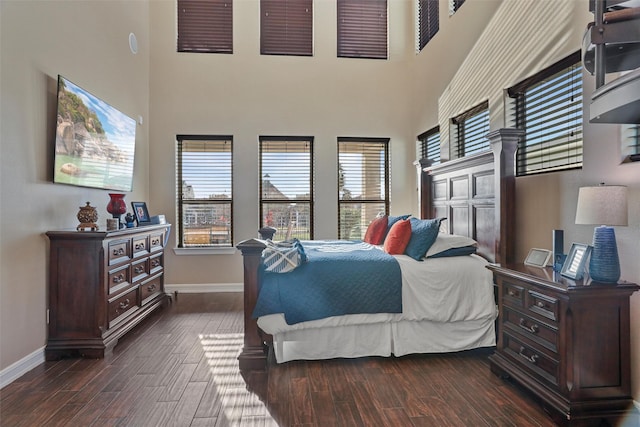 bedroom featuring a towering ceiling and dark wood-type flooring