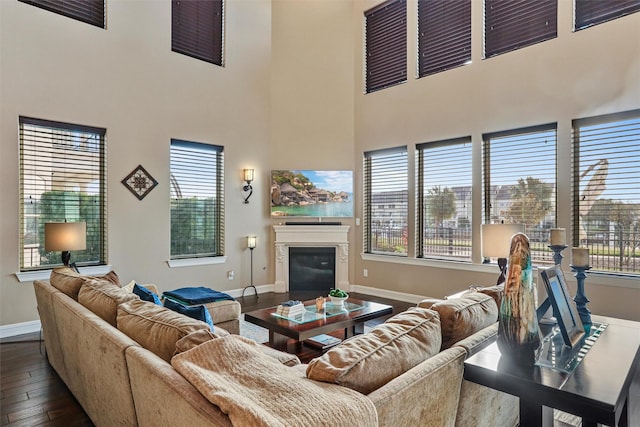 living room featuring dark wood-type flooring, a towering ceiling, and a healthy amount of sunlight