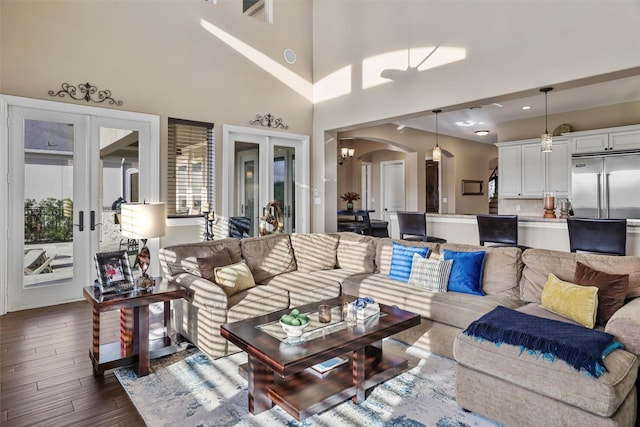 living room featuring a notable chandelier, dark wood-type flooring, high vaulted ceiling, and french doors